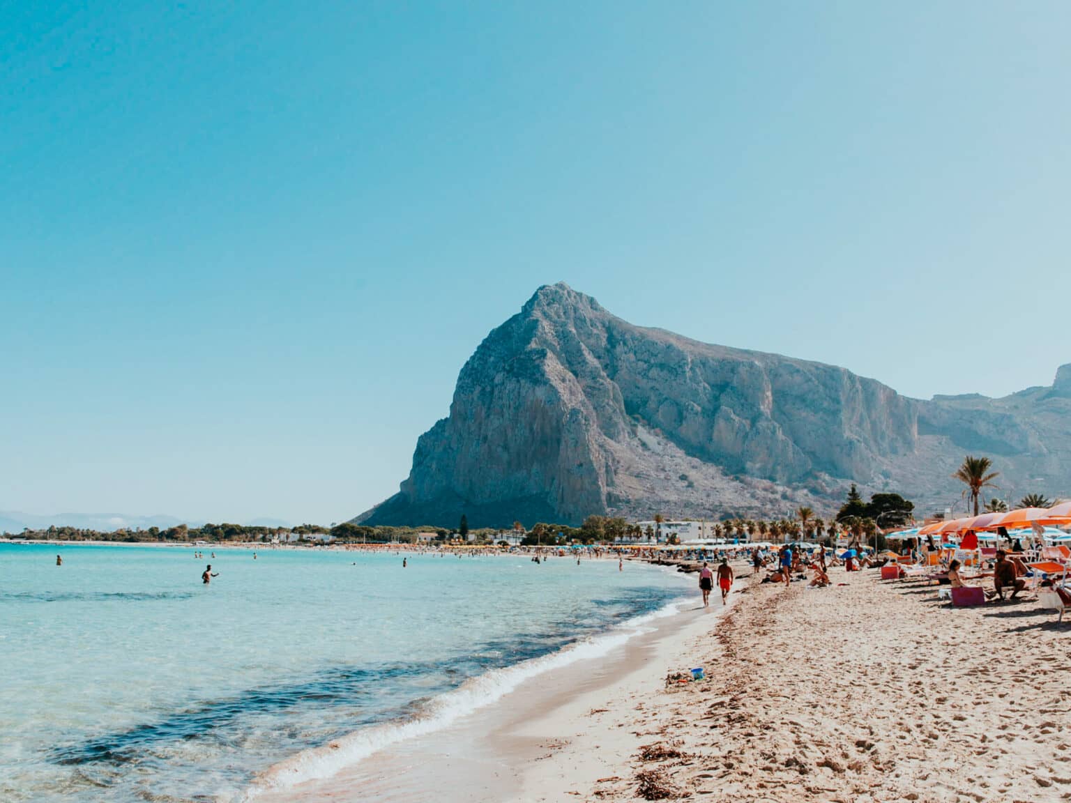 Der Strand von San Vito Lo Capo umgeben von Hügeln und mit türkisblauem Wasser.