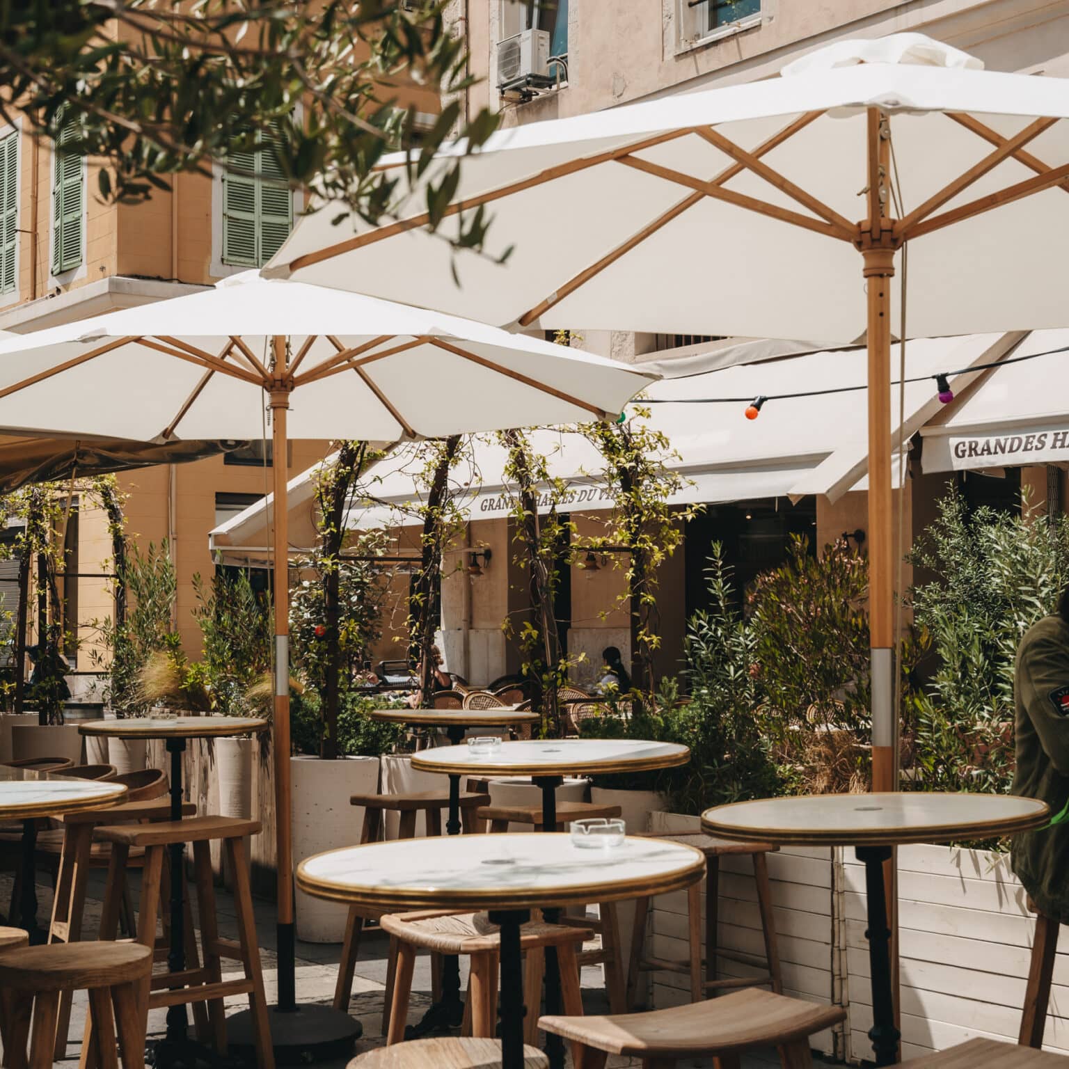 Die Außenterrasse mit weißen Sonnenschirmen des Restaurants Grandes Halles du Vieux Port.