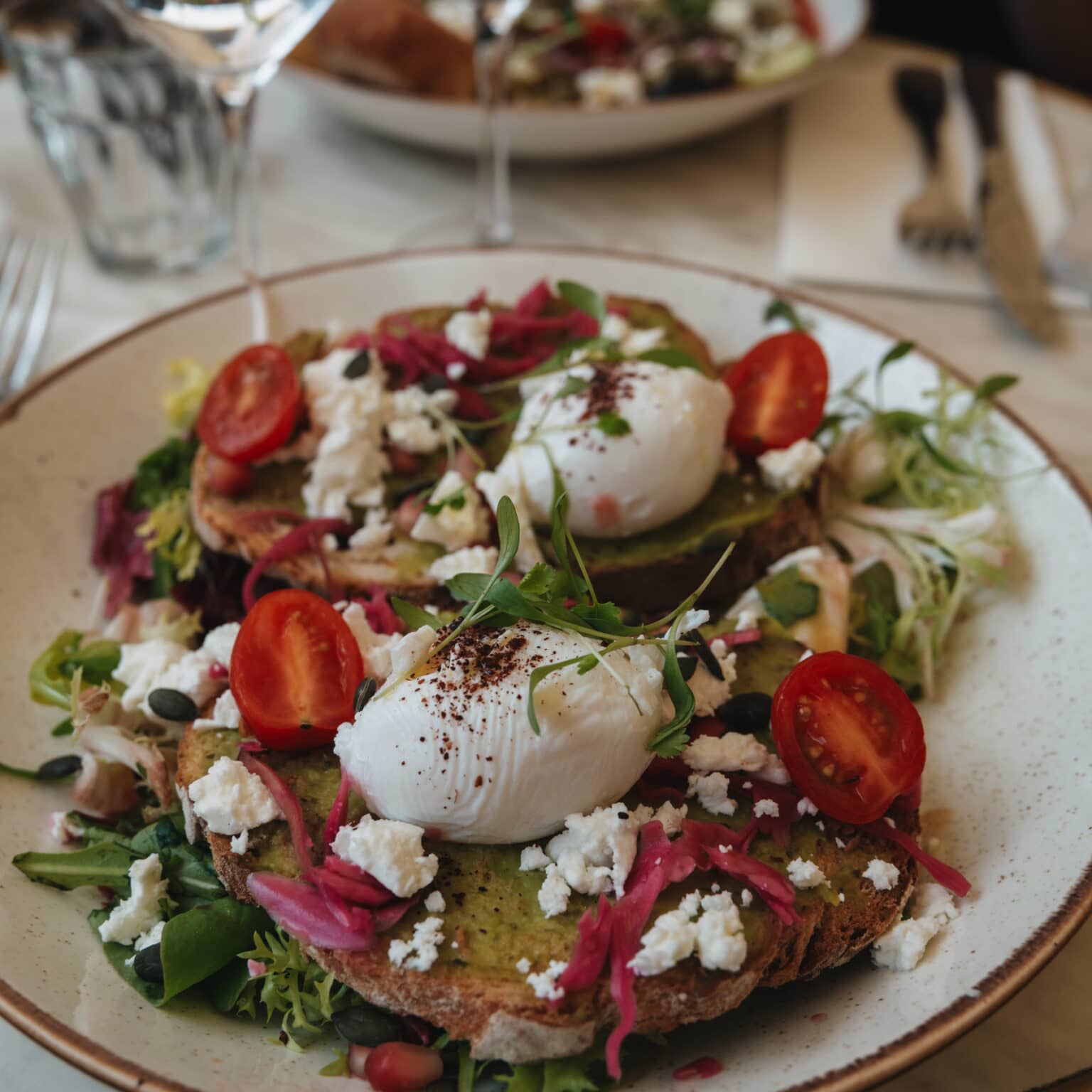 Ein belegtes Brot mit Gemüse und Mozzarella auf einem Teller angerichtet.