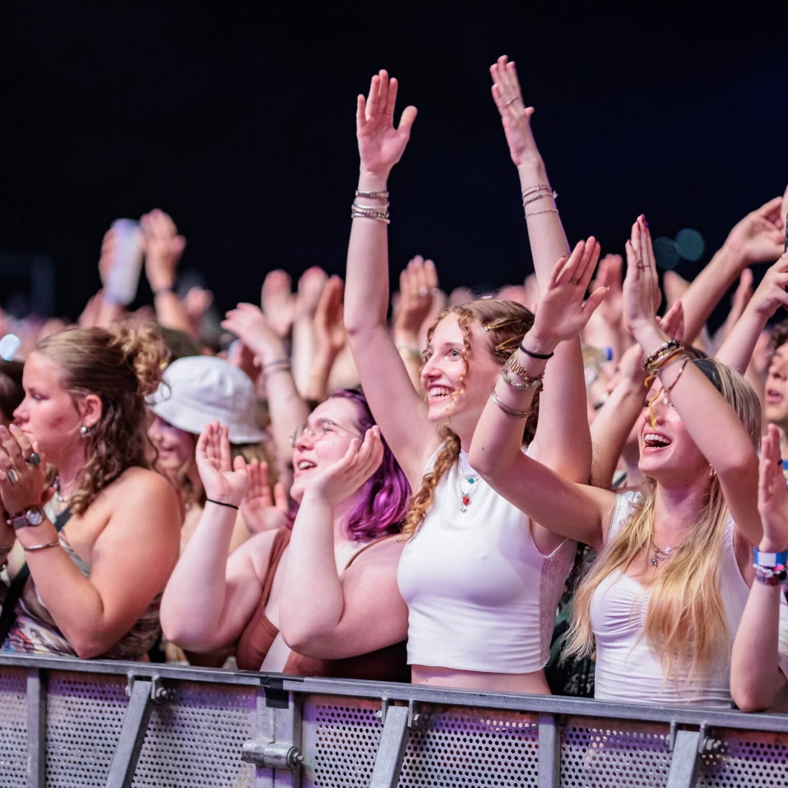 Junge Frauen jubeln in der ersten Reihe hinter der Absperrung bei einem Konzert.