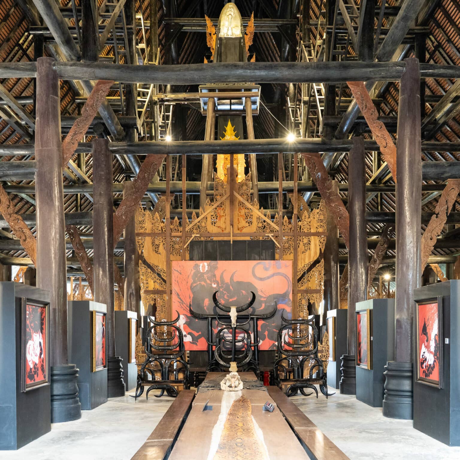 Das Innere eines Gebäudes des Black House in Chiang Rai ist durchzogen von hohen, dunklen Balken und beinhaltet eine Sammlung von Tierknochen und Gemälden.