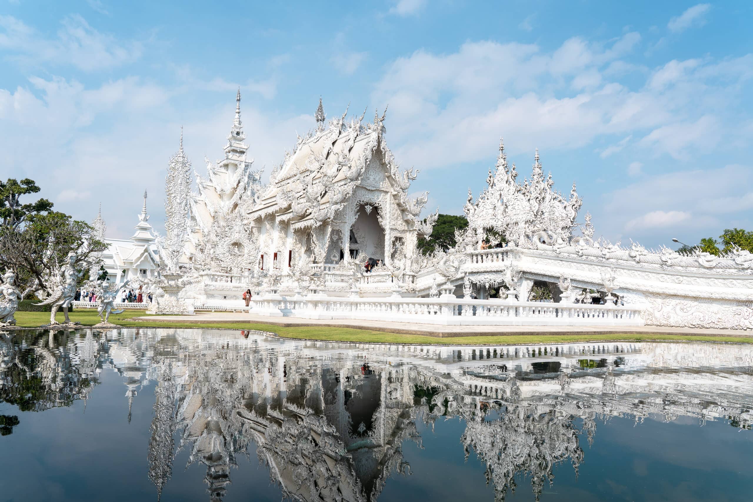 Der weiße Tempel in Chiang Rai spiegelt sich im Wasser des Sees.