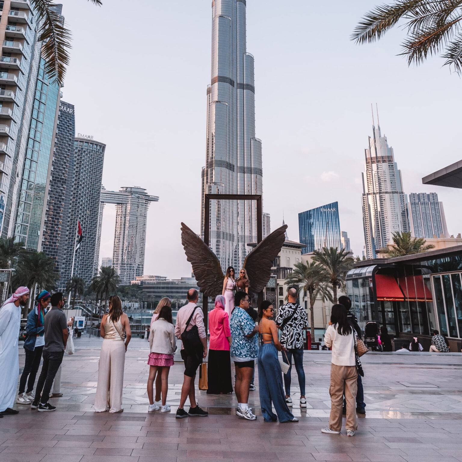 Vor der Skulptur "Wings of Mexico", einem Paar Engelsflügel aus Metall, stehen Menschen Schlange, um sich fotografieren zu lassen. Der Burj Khalifa steht im Hintergrund.