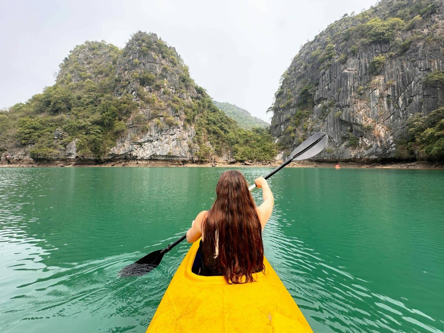 Briggi fährt in einem Kanu durch die Halong-Bucht.