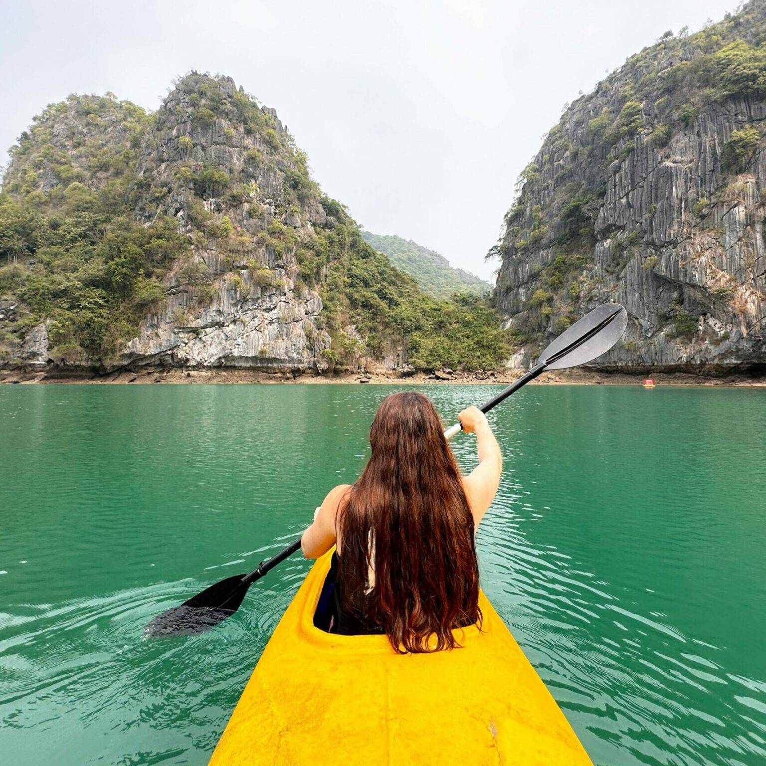 Briggi fährt in einem Kanu durch die Halong-Bucht.