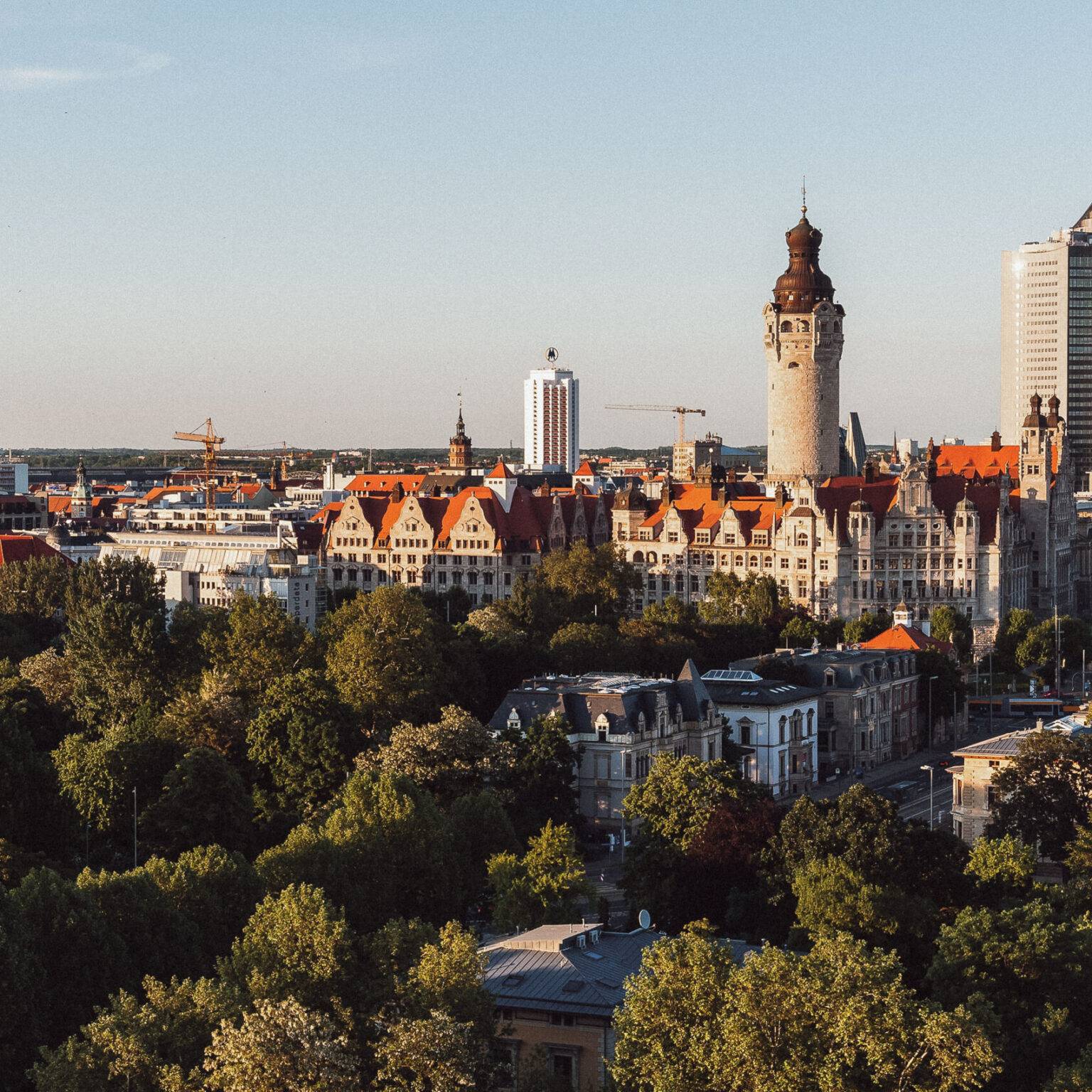Die Skyline von Leipzig mit dem Rathaus bei Sonnenuntergang.