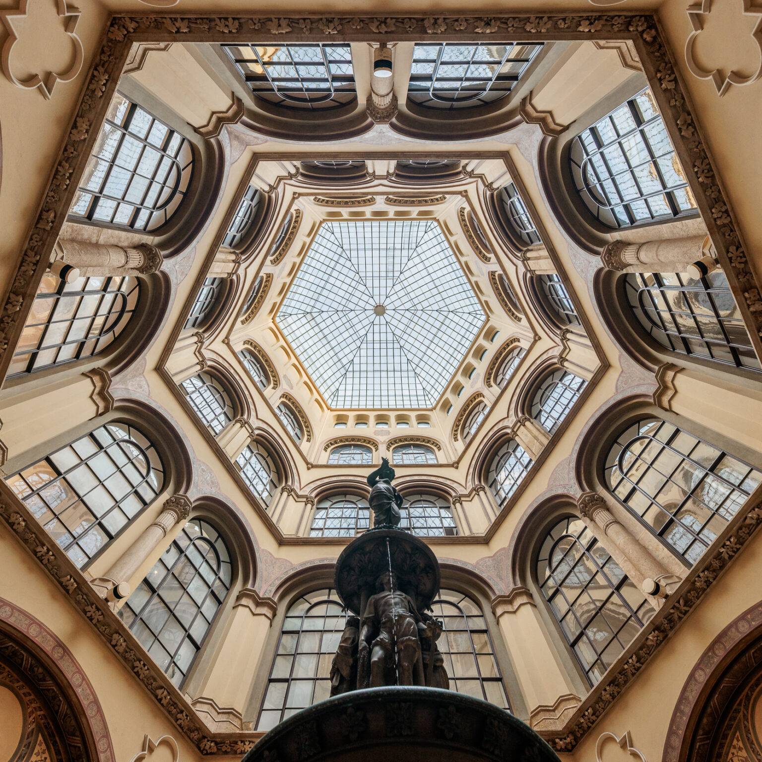 Blick auf ein kunstvolles, sechseckiges Dach mit Fenstern und einer zentralen Statue in der Ferstelpassage.