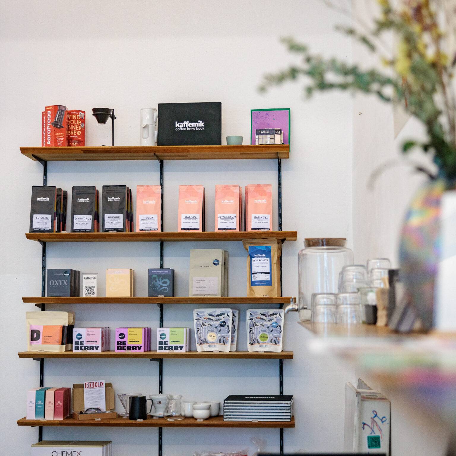 Regal mit verschiedenen Kaffee-Produkten im kaffeemik und eine Vase mit Blumen im Vordergrund.