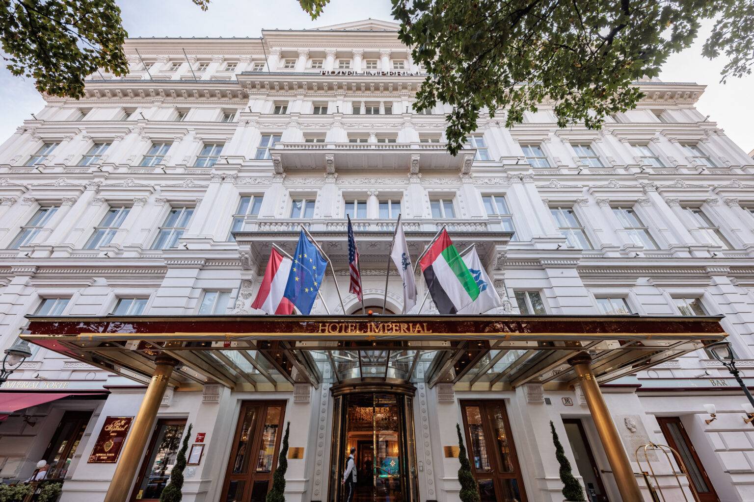 Fassade des eleganten Hotels Imperial mit mehreren Flaggen und einem Eingangsbereich unter einem Vordach.