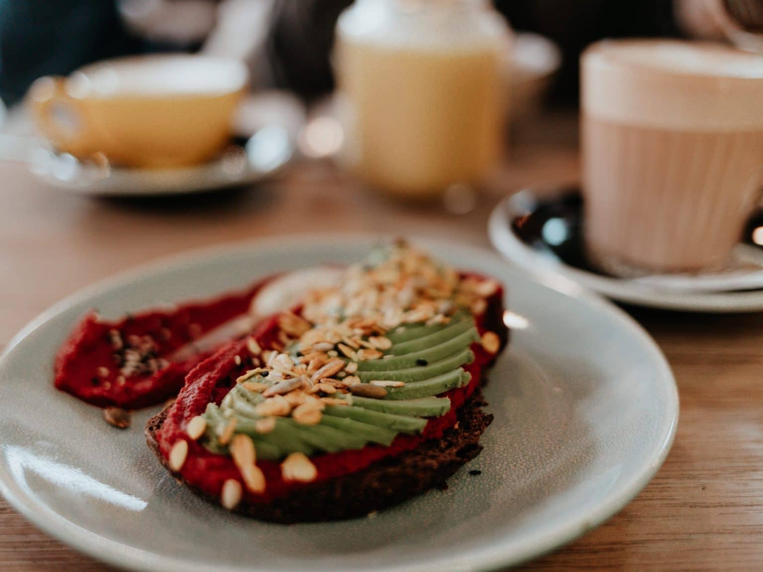 Ein leckeres Brot belegt mit Avocado, im Hintergrund Kaffee.