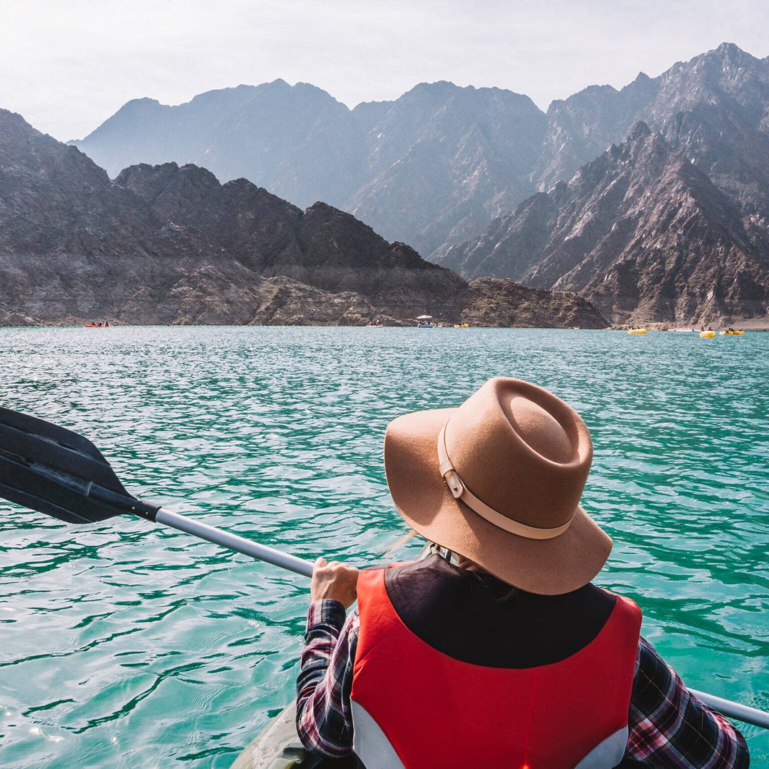 Eine Frau mit Hut und Paddel sitzt in einem Kajak auf dem Hatta-Stausee bei Dubai.
