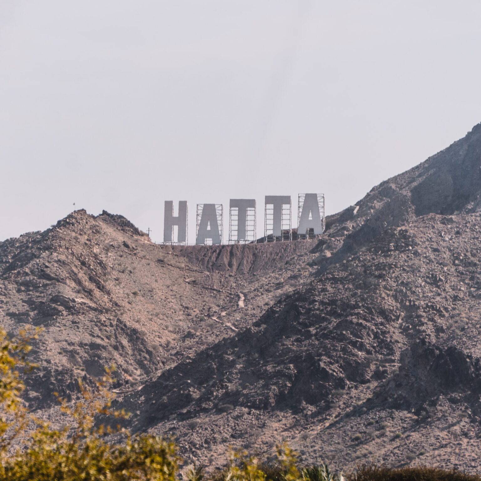 Auf einem steinigen Gipfel steht mit großen weißen Buchstaben der Schriftzug "HATTA".
