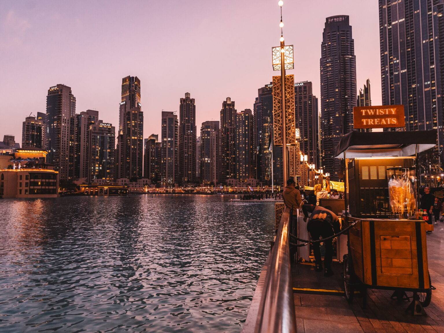 Der See am Fuße des Burj Khalifa umgeben von Hochhäusern bei Sonnenuntergang.