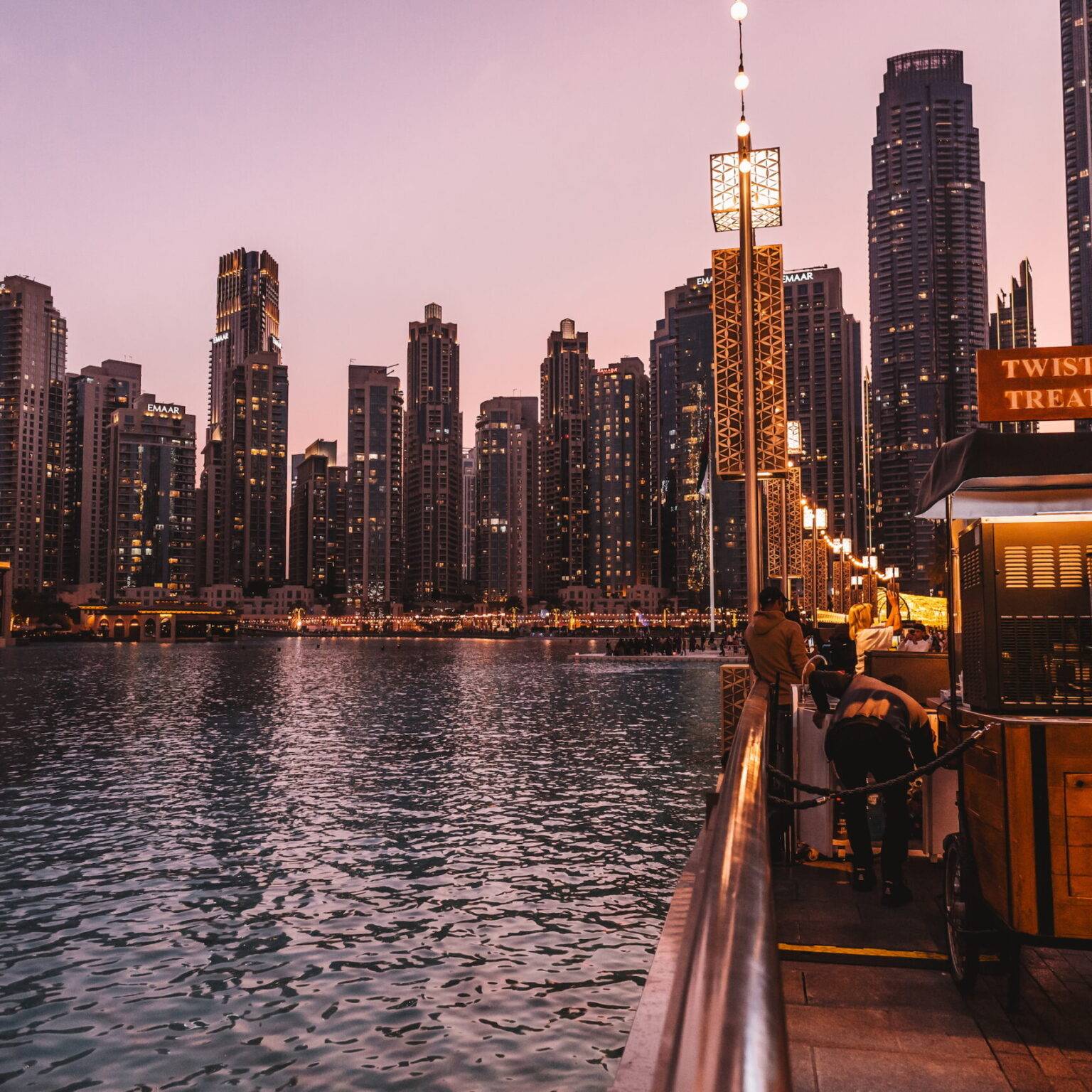 Der See am Fuße des Burj Khalifa umgeben von Hochhäusern bei Sonnenuntergang.