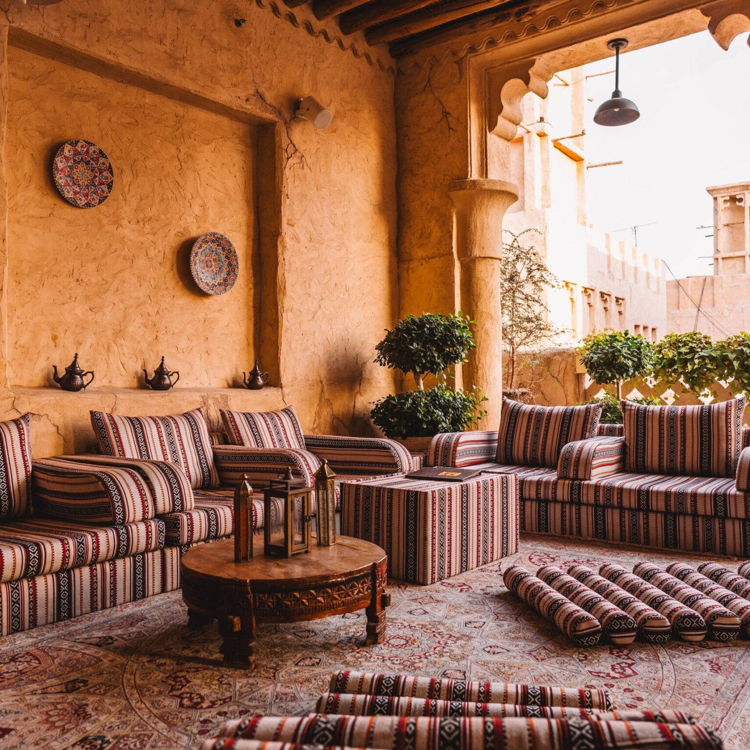 Eine halboffene Sitzecke mit bunt gemusterten Polstern im Al Seef Heritage Hotel.