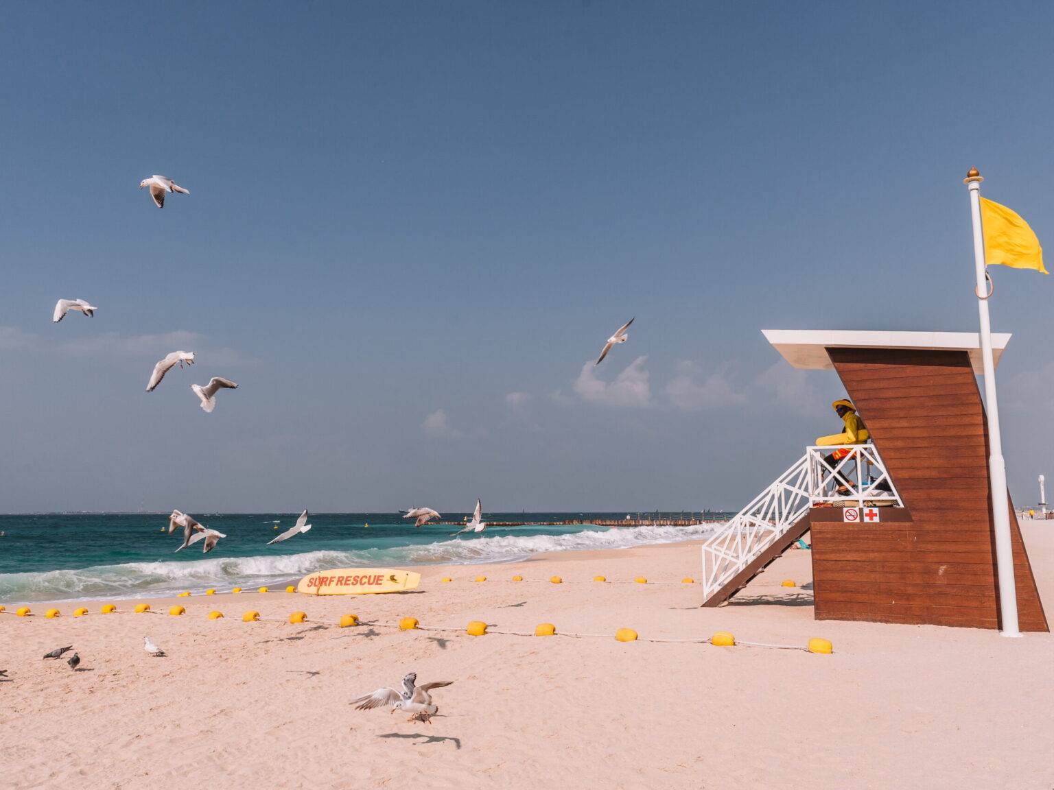 Der Umm Suqeim Strand in Dubai mit Möven und einem Rettungsschwimmer auf einem kleinen überdachten Turm.