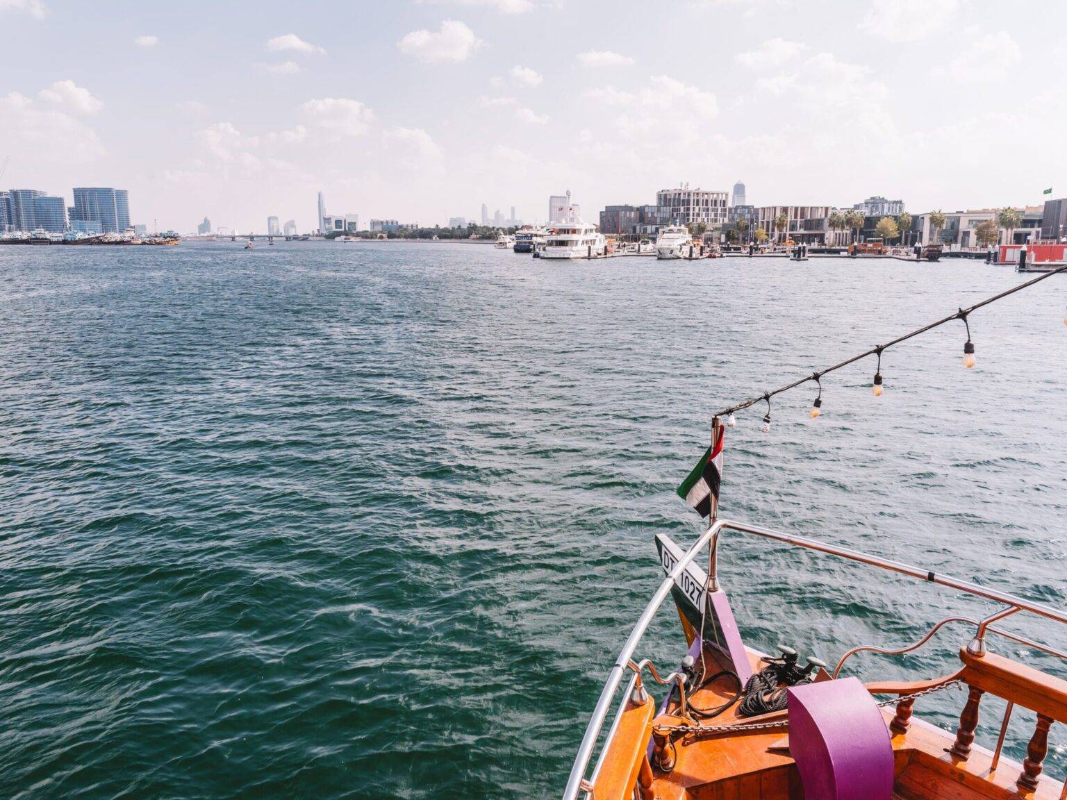 Der Bug eines Schiffs auf dem Dubai Creek mit anderen Booten und Hochhäusern im Hintergrund.