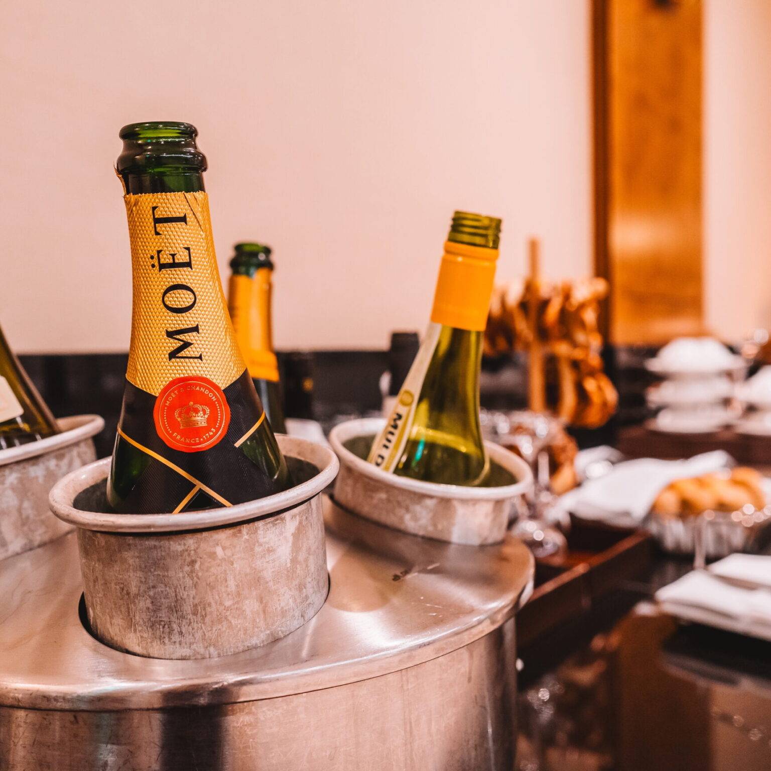 Das Buffet in der Emirates-Lounge am Flughafen München mit einem Sektkühler im Vordergrund, der mit Sekt- und Champagner-Flaschen gefüllt ist.