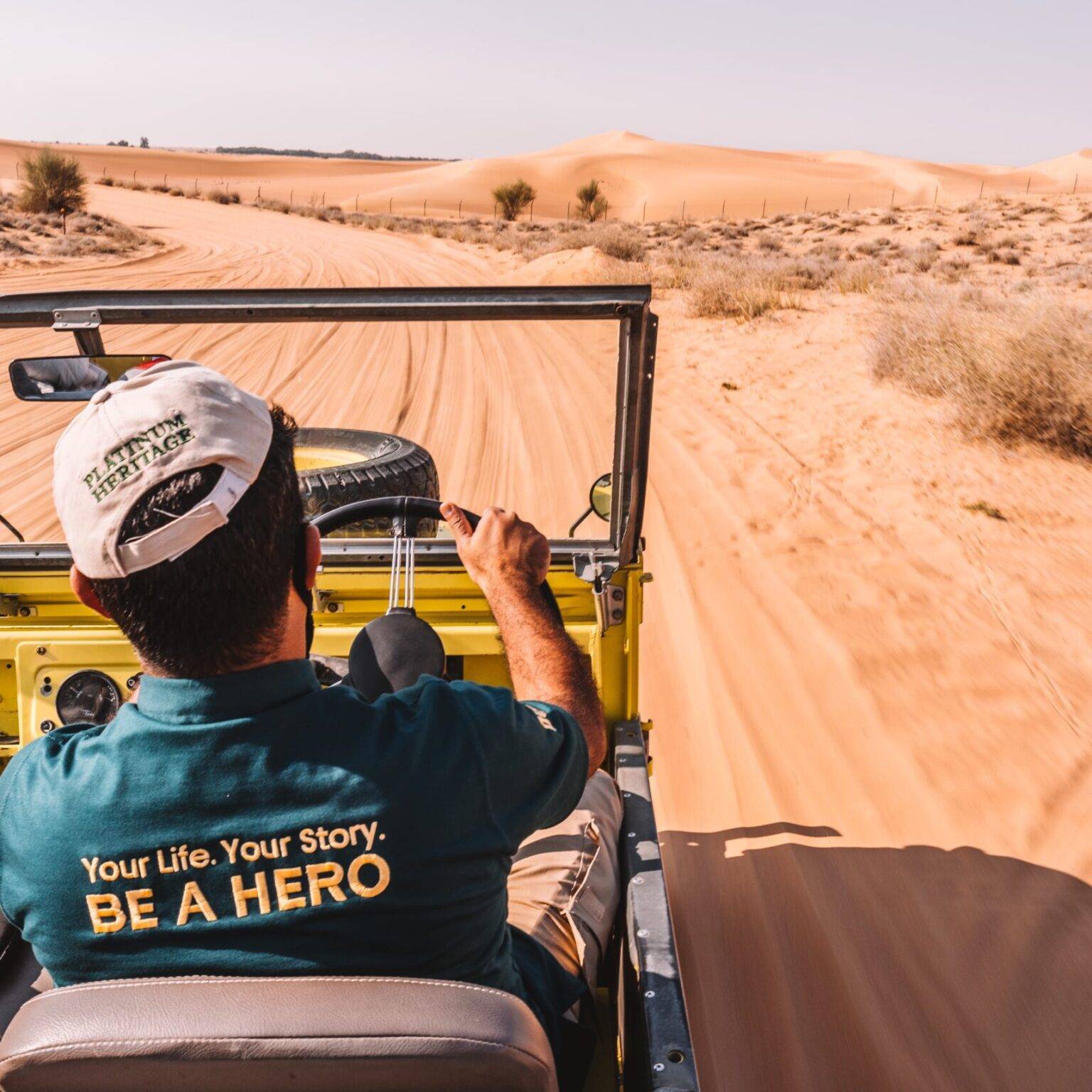 Ein Mann fährt einen Geländewagen ohne Dach durch die Wüste von Dubai.