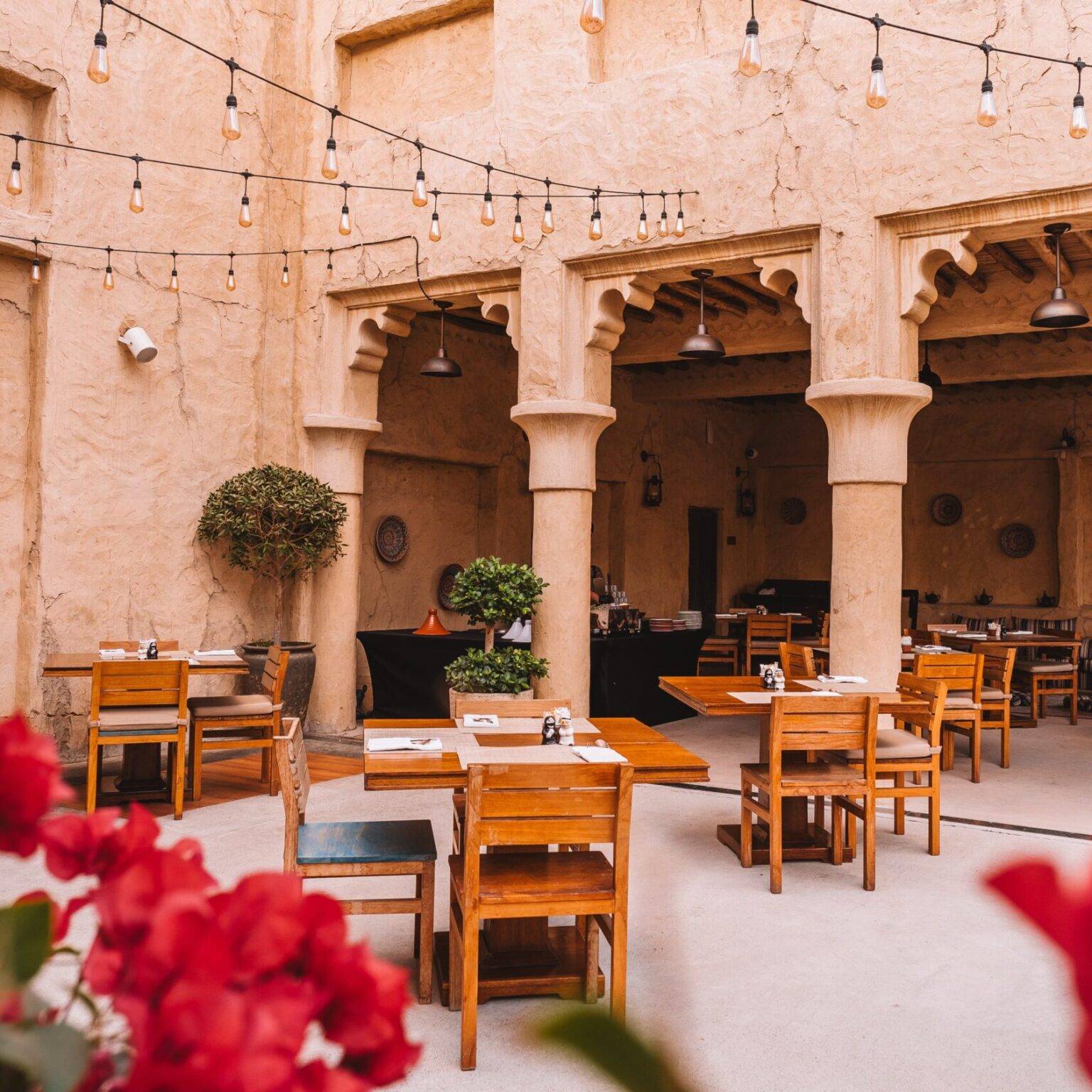 Der Restaurantbereich des Al Seef Heritage Hotels in Dubai mit hohen Säulen und lehmverputzten Wänden.