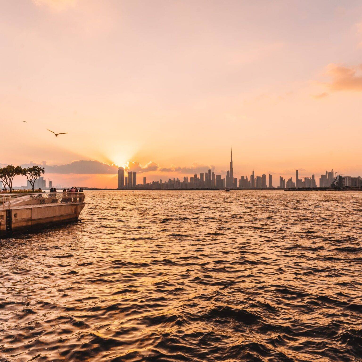 Der Creek Habour in Dubai mit der Skyline der Stadt im Hintergrund bei Sonnenuntergang.