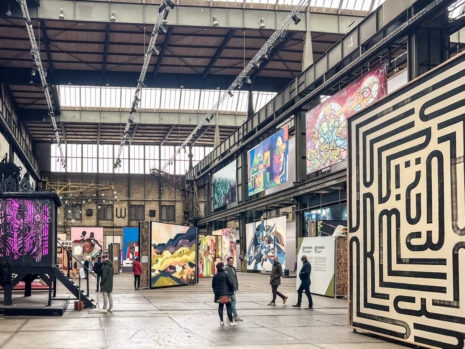 Innenansicht des STRAAT Museums in Amsterdam-Noord mit monumentalen Streetart-Kunstwerken in einer weitläufigen Industriehalle.