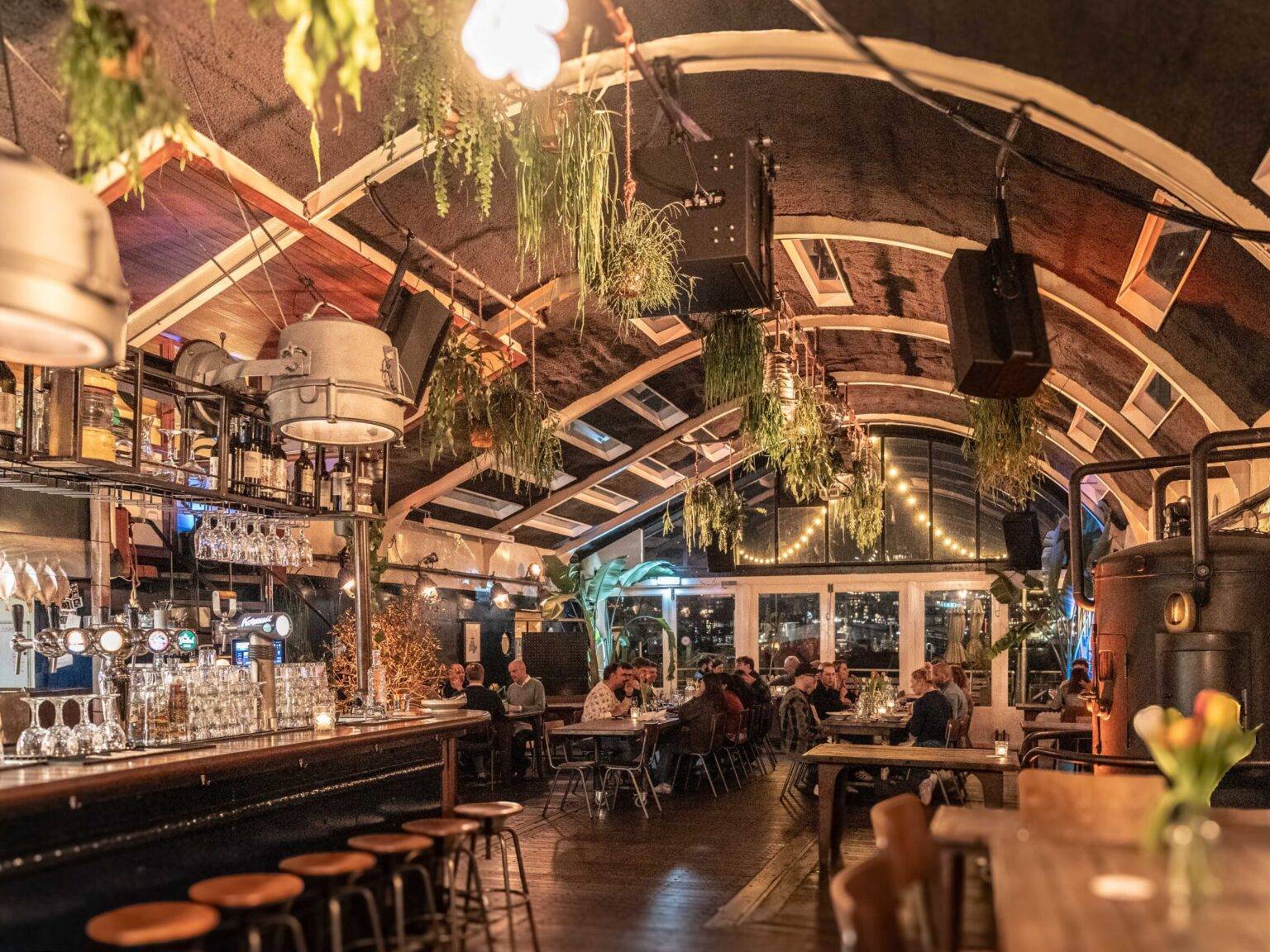 Das Restaurant Ferry von innen mit Bar und von der Decke hängenden Pflanzen.