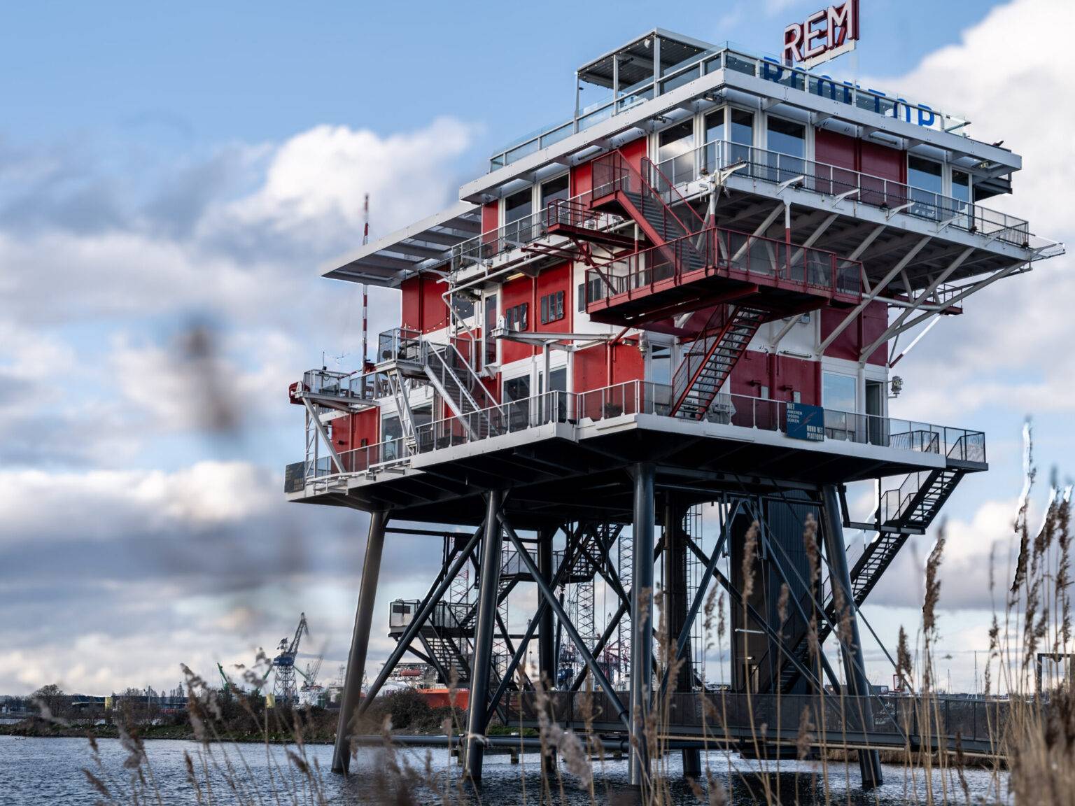 Außenansicht des Restaurants REM Eiland in Amsterdam, ein ehemaliger Sendeturm auf Stelzen über dem Wasser mit industriellem Design.
