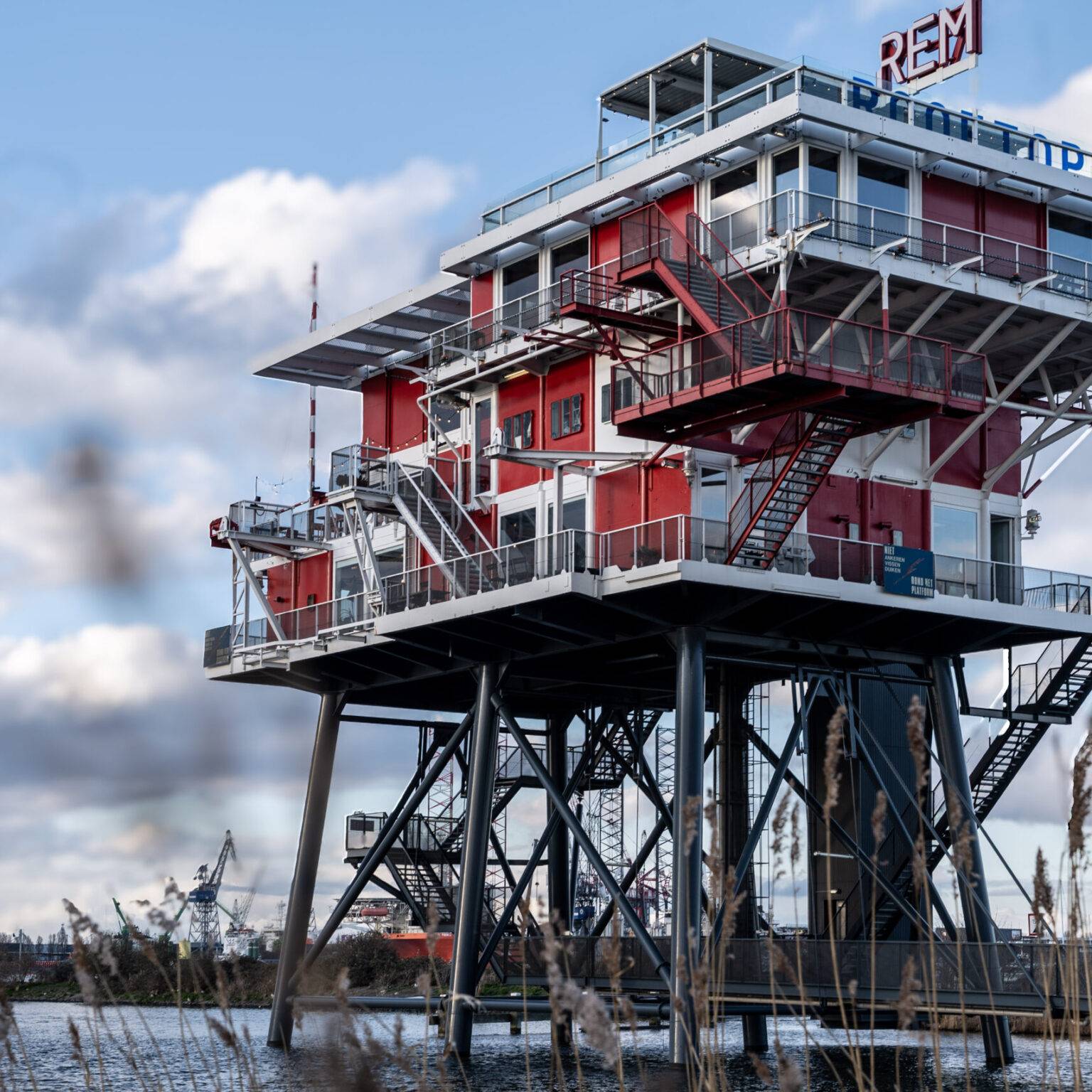 Außenansicht des Restaurants REM Eiland in Amsterdam, ein ehemaliger Sendeturm auf Stelzen über dem Wasser mit industriellem Design.
