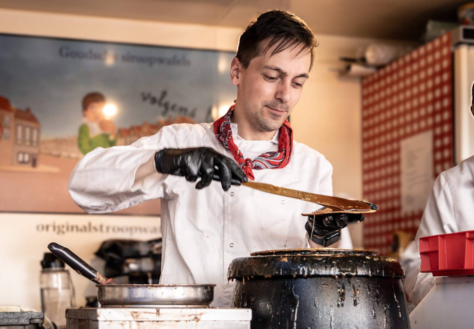 Ein Mitarbeiter verteilt Sirup auf einer Stroopwafel.