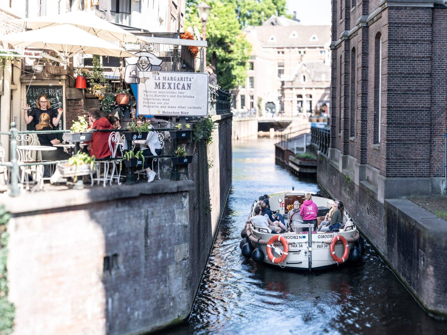 Ein Touristenboot fährt in Amsterdams Altstadt unter einer kleinen Brücke durch.