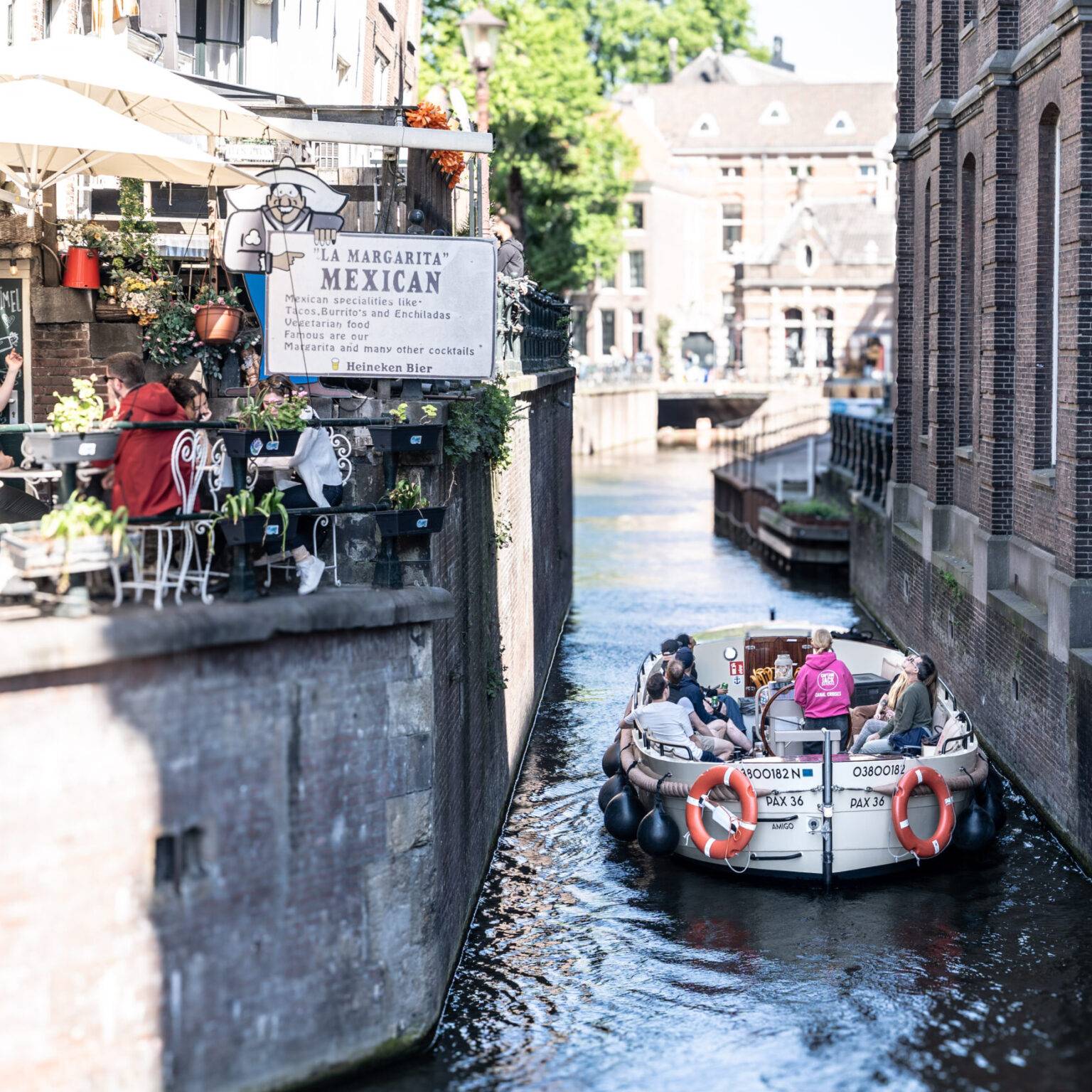Ein Touristenboot fährt in Amsterdams Altstadt unter einer kleinen Brücke durch.