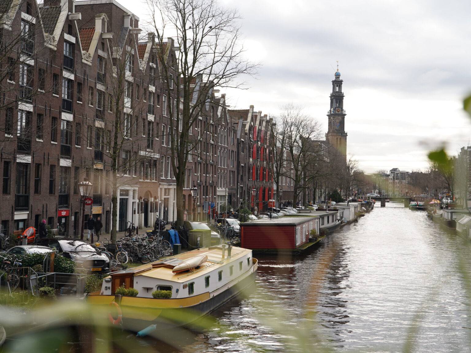 Blick über die Prinsengracht im Amsterdamer Jordaan-Viertel mit typischen Grachtenhäusern und der Westerkerk im Hintergrund.