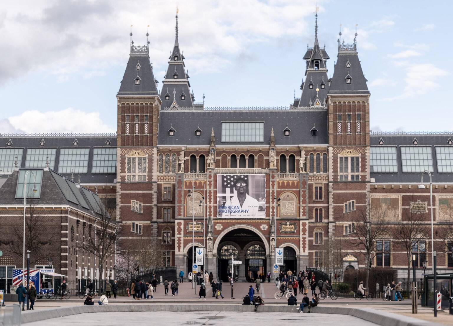 Außenansicht des Rijksmuseum in Amsterdam bei Tageslicht, mit historischer Fassade und Besucher:innen davor