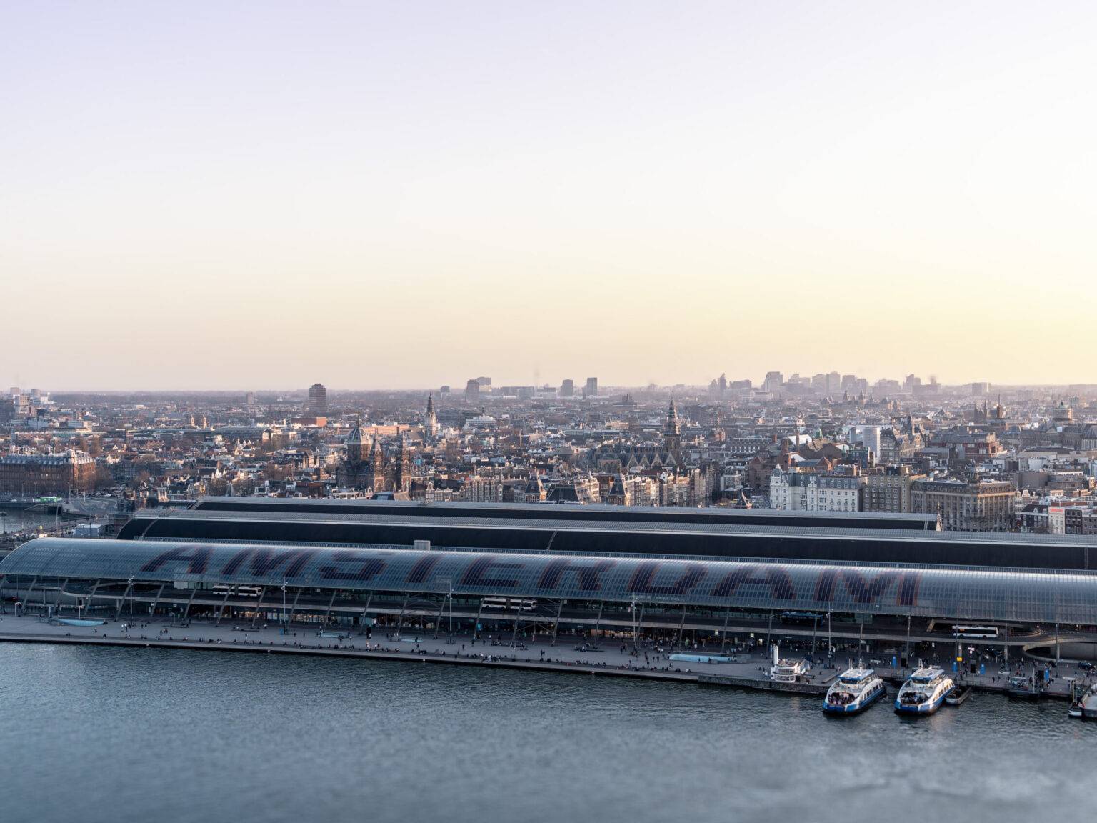 Ausblick vom A´DAM Tower auf Amsterdam und den Hauptbahnhof mit Amsterdam Schriftzug bei Sonnenuntergang.