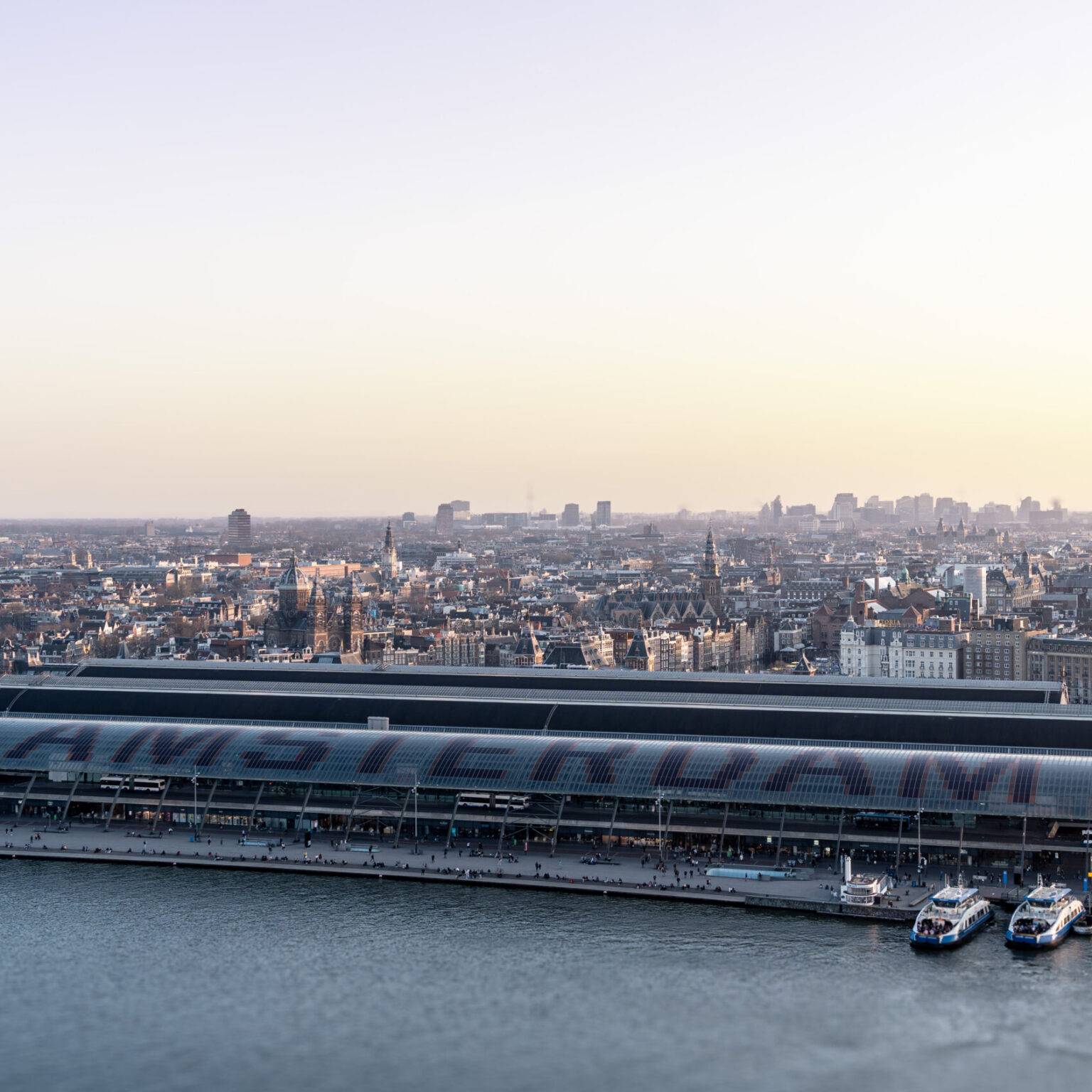Ausblick vom A´DAM Tower auf Amsterdam und den Hauptbahnhof mit Amsterdam Schriftzug bei Sonnenuntergang.