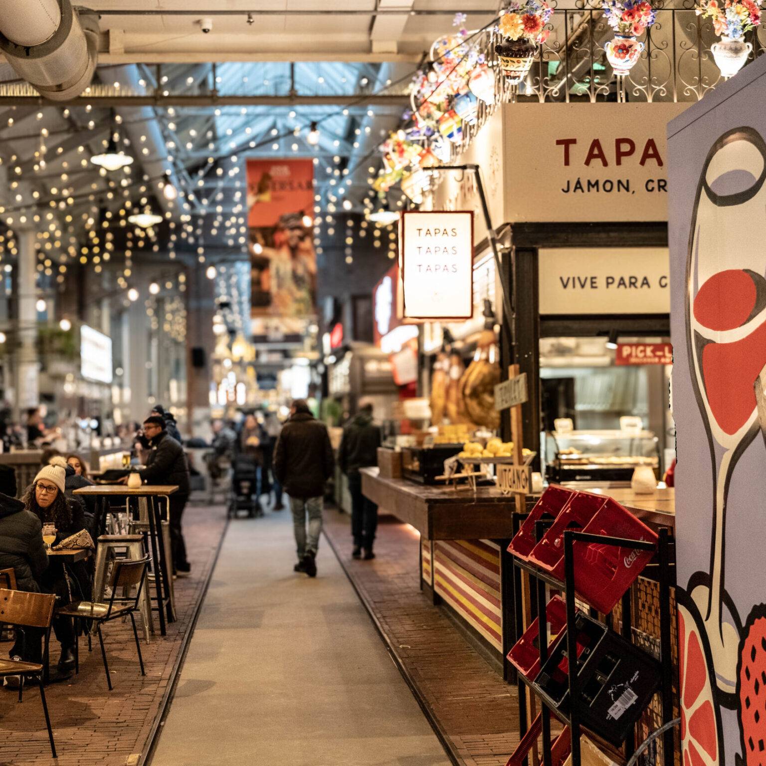 Innenaufnahme der Foodhallen in Amsterdam Oud-West mit verschiedenen Streetfood-Ständen und Besuchern.