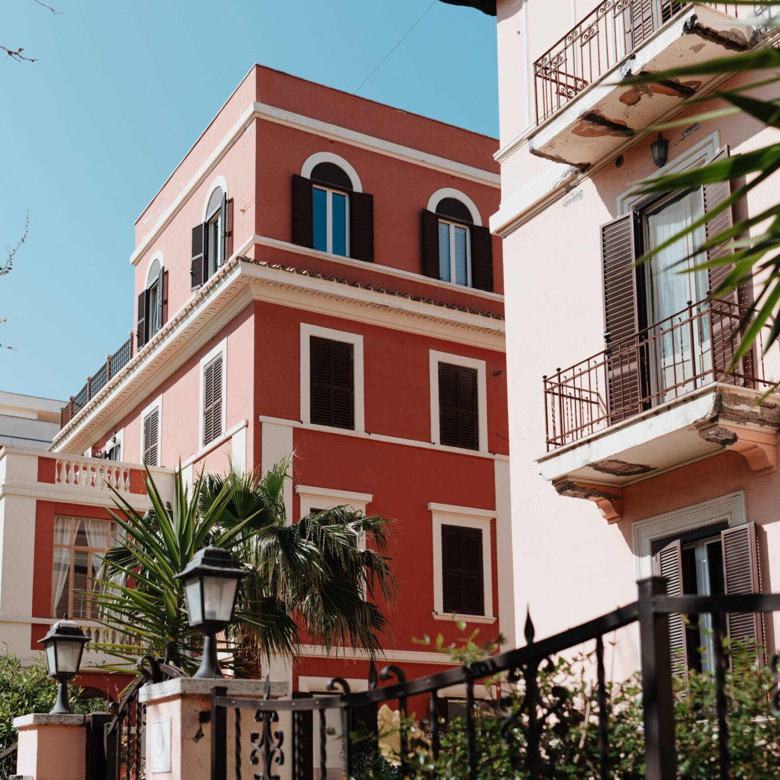 Historische Sommerresidenzen mit farbenfrohen Fassaden und Palmen in Lido di Ostia.