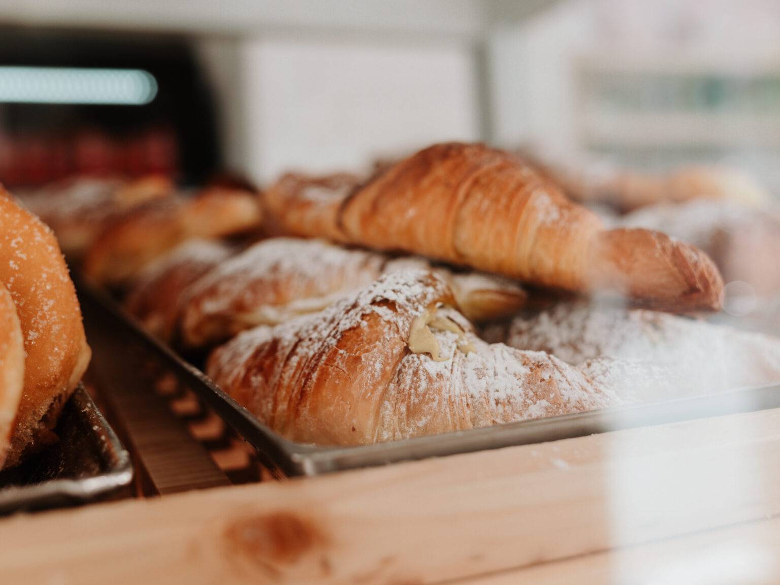 Frisch gebackene, mit Puderzucker bestäubte Cornetti in einer italienischen Bäckerei.