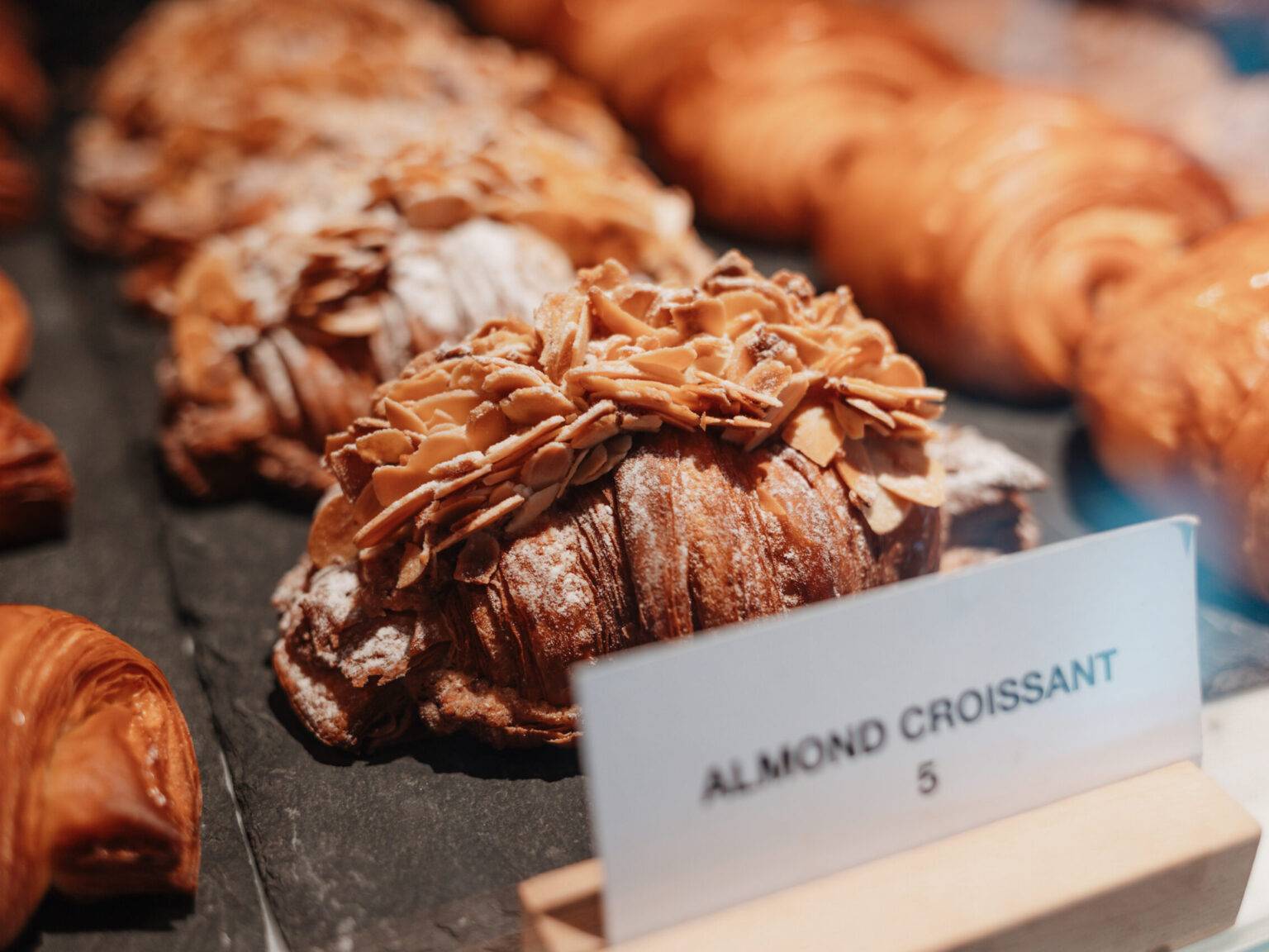 Frisch gebackenes Mandelcroissant mit Mandelsplittern in der Vitrine des Barnum Cafés.