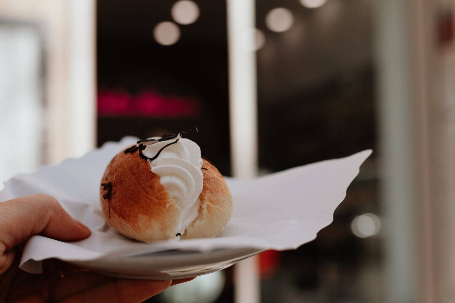 Maritozzo mit Schlagsahne in der Hand vor der Pasticceria Dolce Maniera in Rom.