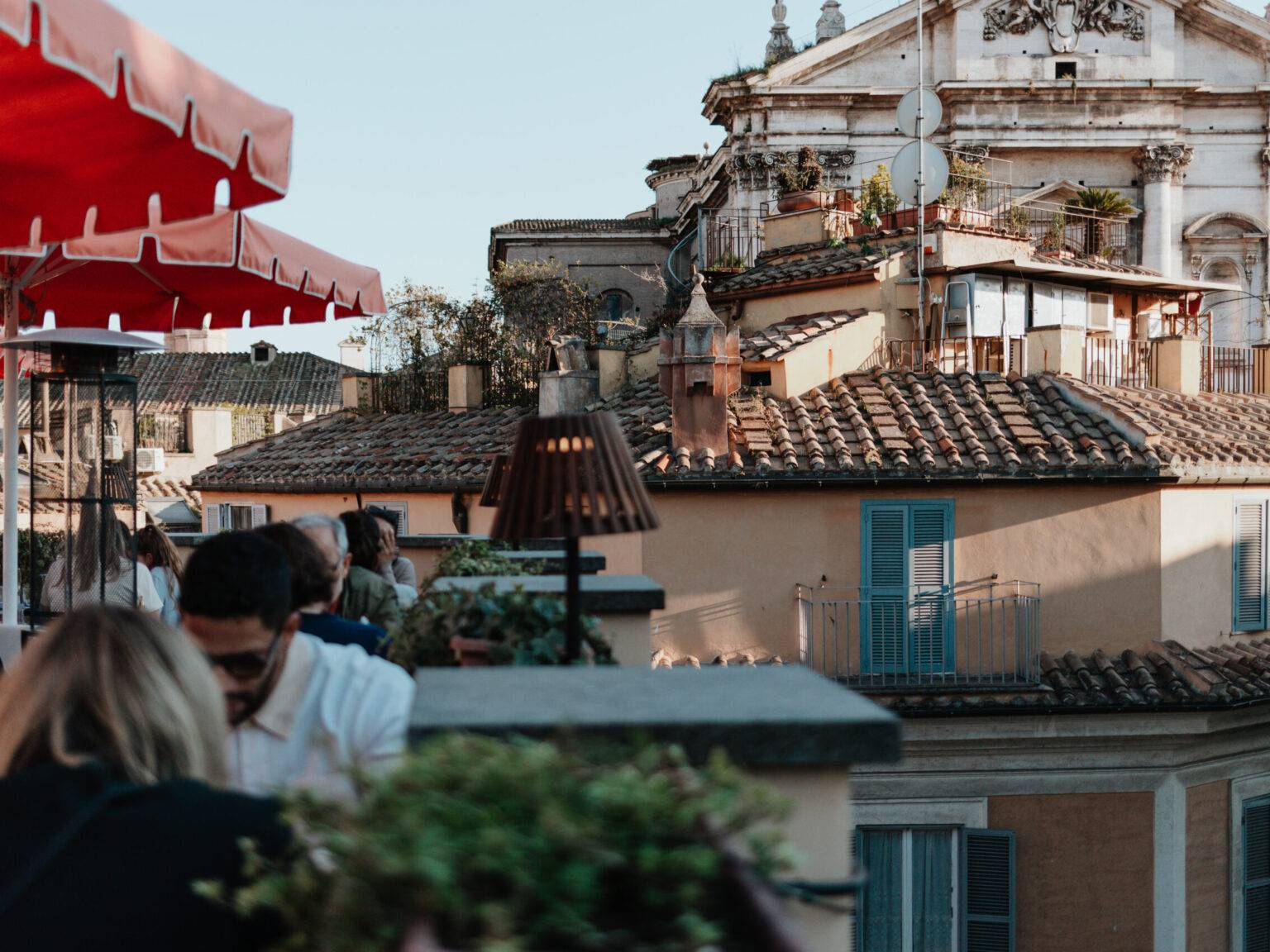 Gäste auf der Rooftop Bar des 9Hotel Cesari mit Blick auf römische Dächer und Kirche Sant’Ignazio di Loyola.