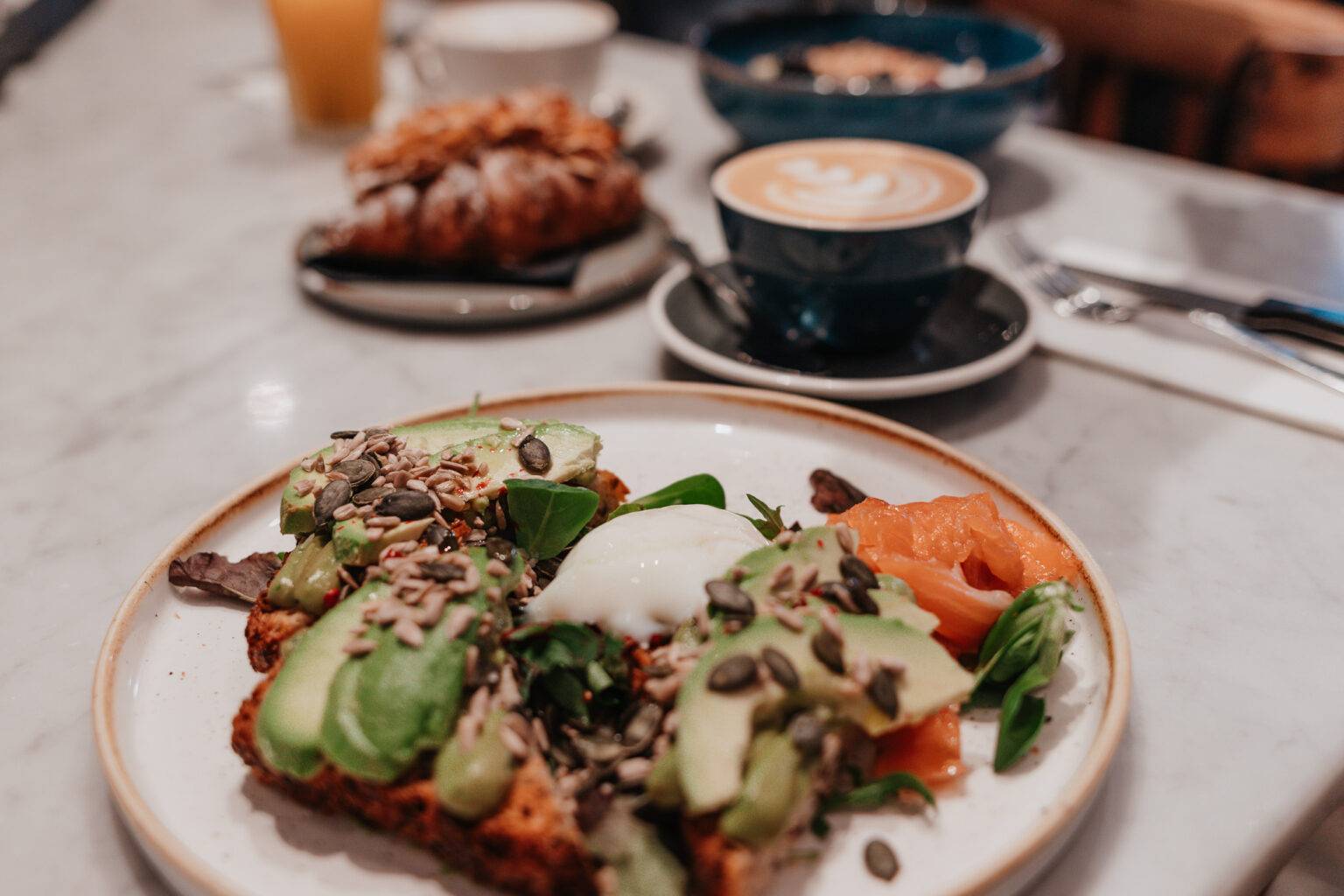 Frühstücksteller im Barnum in Rom mit Avocado-Toast, pochiertem Ei, Lachs und Kaffee.