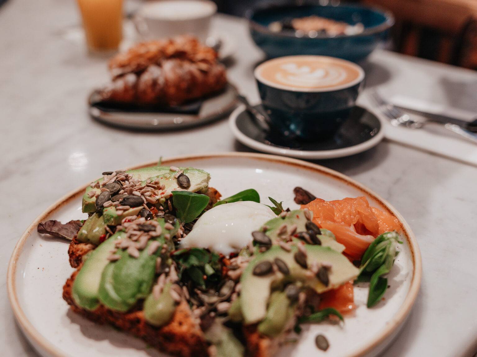 Frühstücksteller im Barnum in Rom mit Avocado-Toast, pochiertem Ei, Lachs und Kaffee.