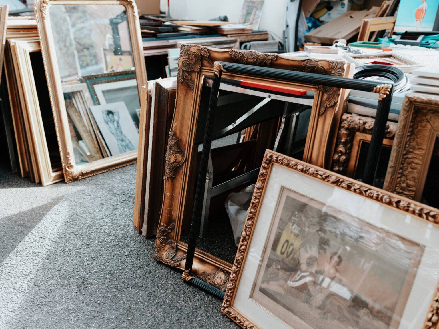 Ein Marktstand mit reihenweise antiken Bilderrahmen und Kunstwerken.