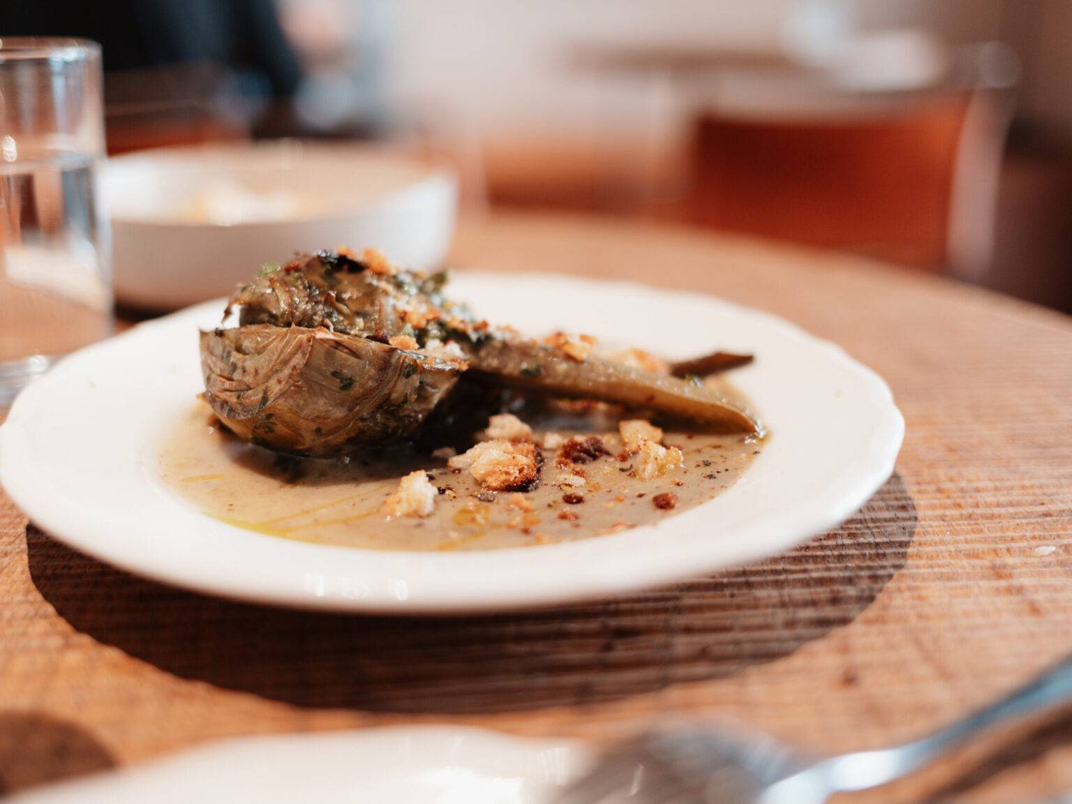Gefüllte Artischocke auf weißem Teller, serviert im Restaurant Ruma Bottega in Rom.