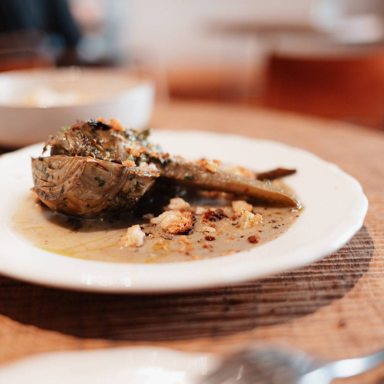 Gefüllte Artischocke auf weißem Teller, serviert im Restaurant Ruma Bottega in Rom.