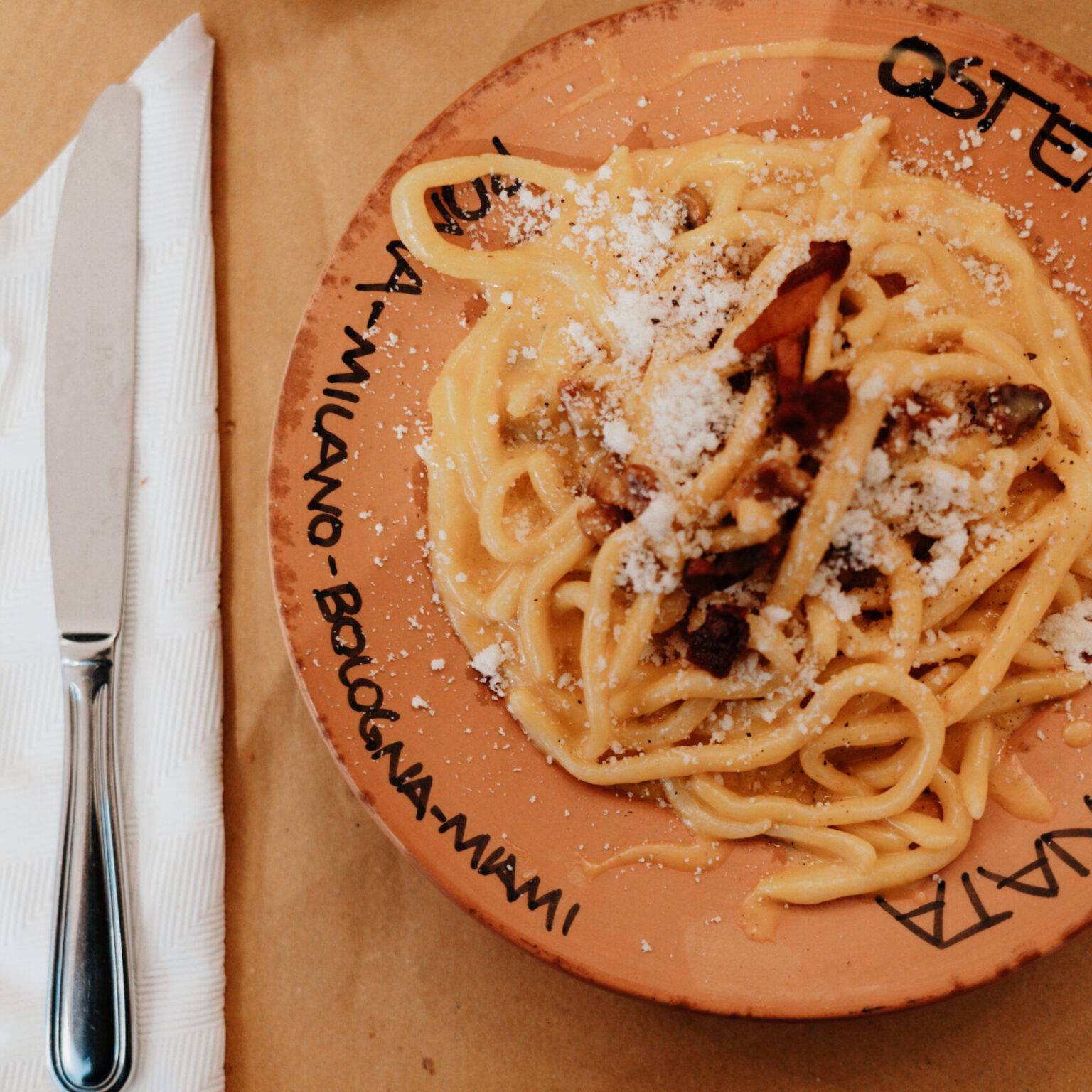 Portion Pasta alla Carbonara auf einem Teller mit Osteria da Fortunata-Schriftzug.