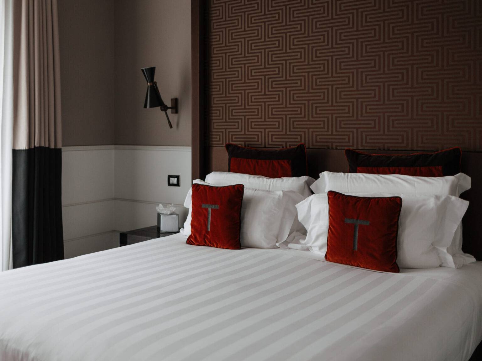 Ein Bett in einem Hotelzimmer im The Tribune mit roten Samtkissen.