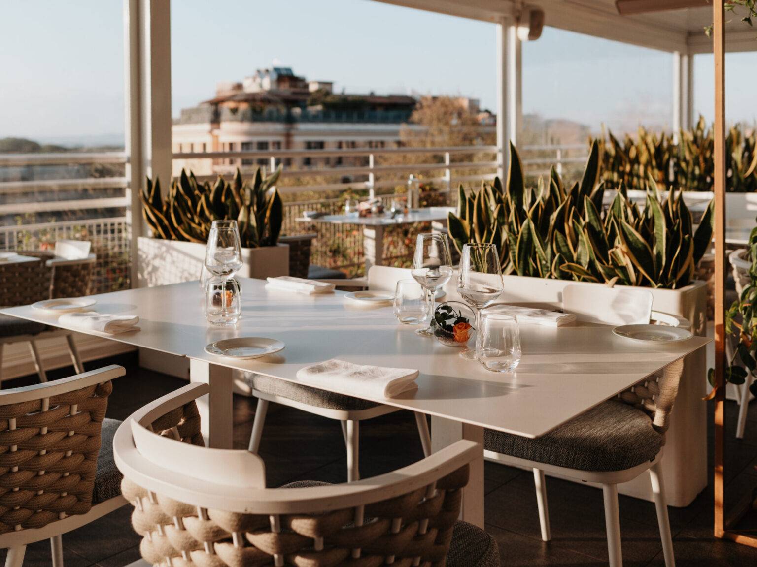 Ein gedeckter Tisch mit vier Stühlen auf der Dachterrasse des The Tribune Hotels.